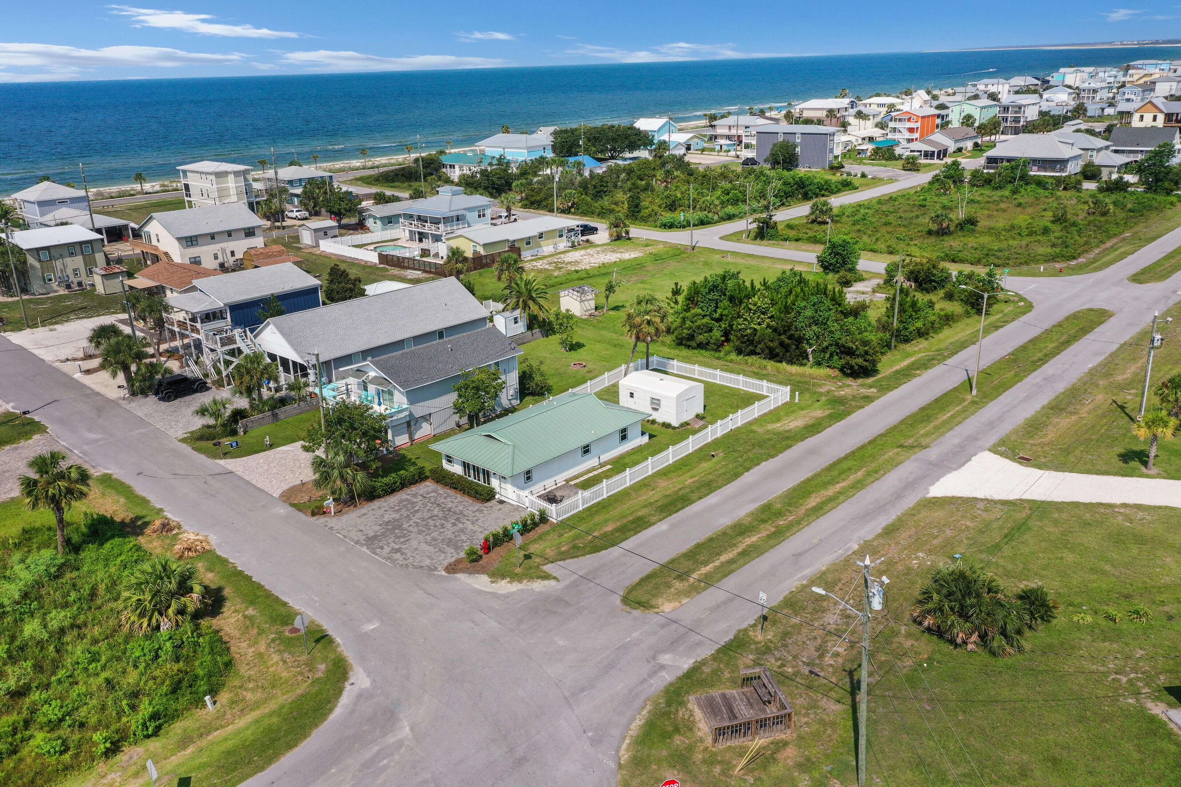 An aerial view of a residential area with houses, roads, and a beach in the background.