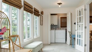 A laundry room with a washing machine and dryer, a bench, and a chair. - 1st Street Bungalow (Port St. Joe)