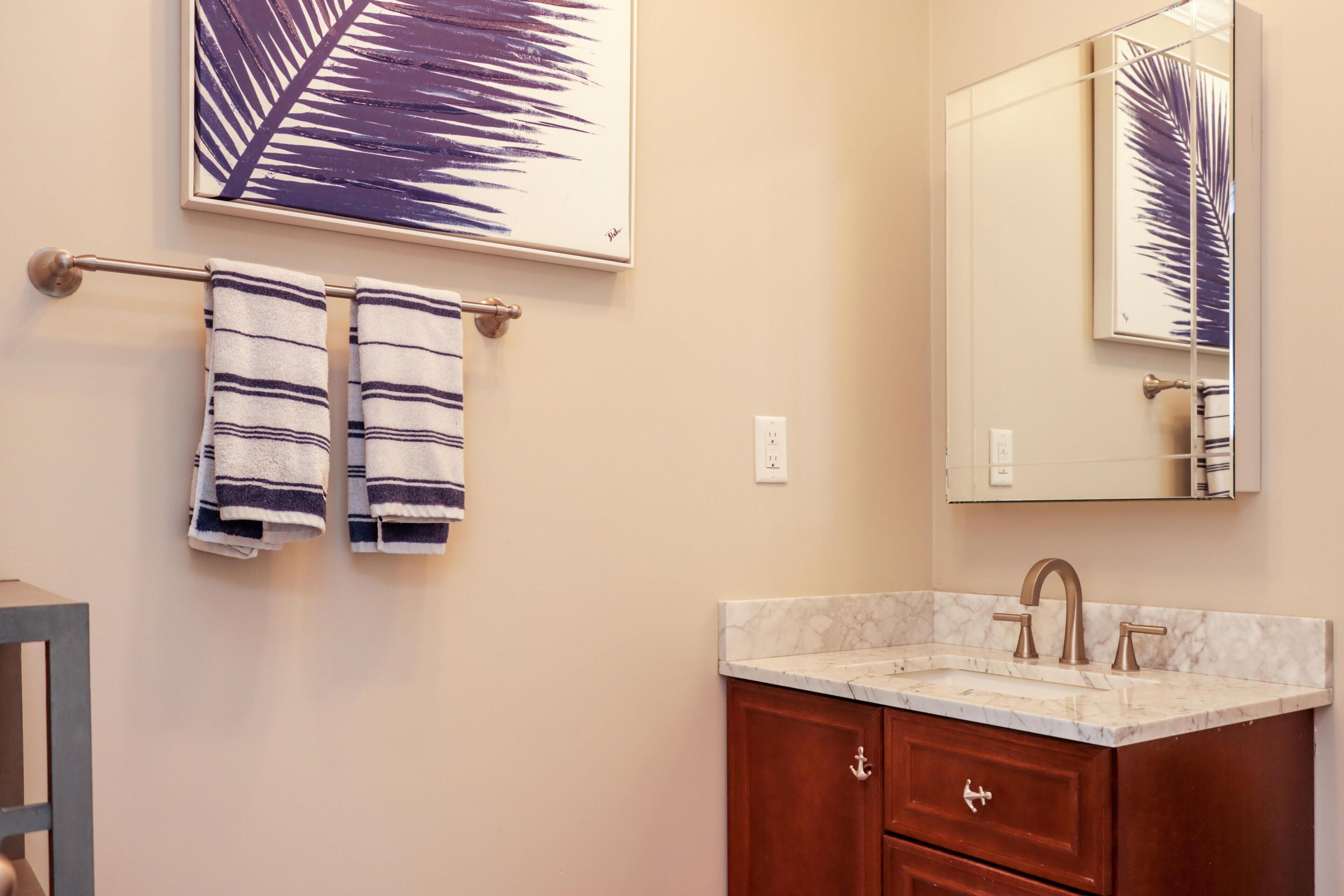 Une salle de bain avec un lavabo en marbre, des meubles en bois et deux serviettes suspendues à un porte-serviettes.