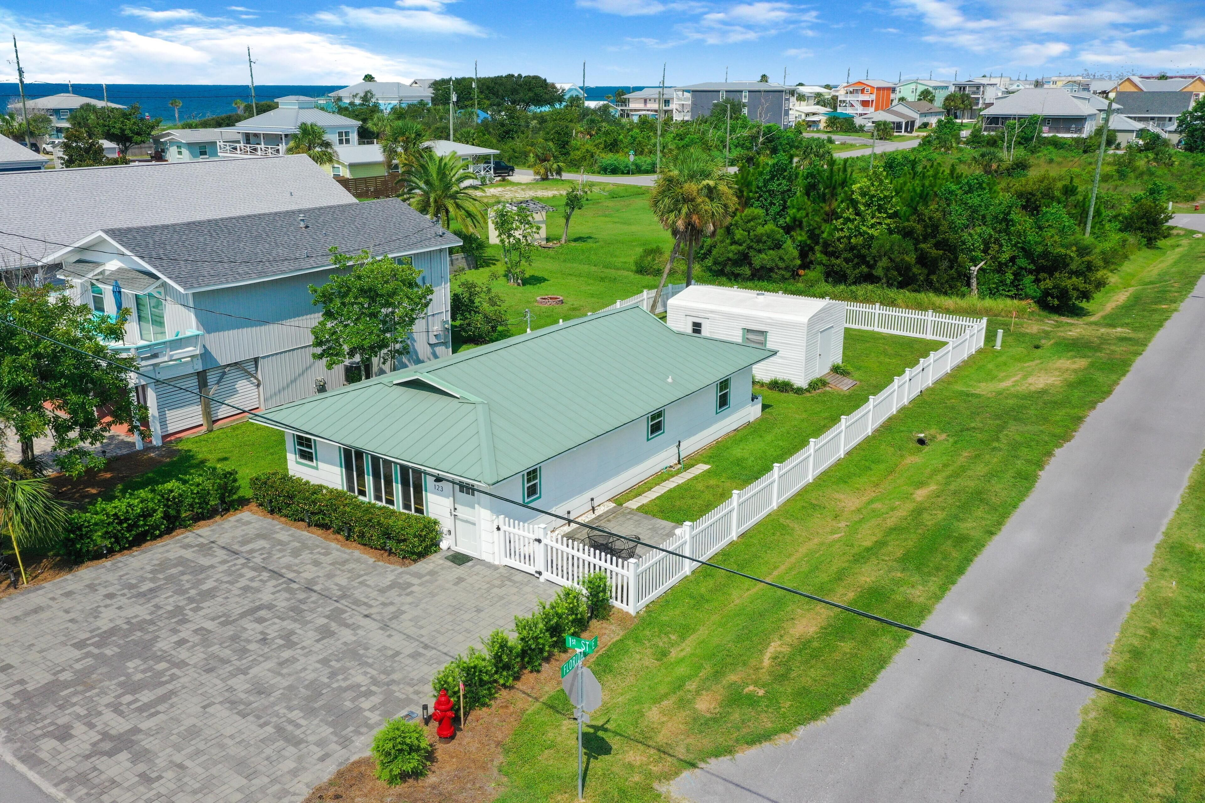 A residential area with houses, a green lawn, and a white picket fence.