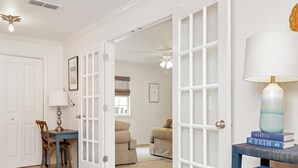 A room with a dining area, a sofa, a lamp, and a bookshelf. - 1st Street Bungalow (Port St. Joe)