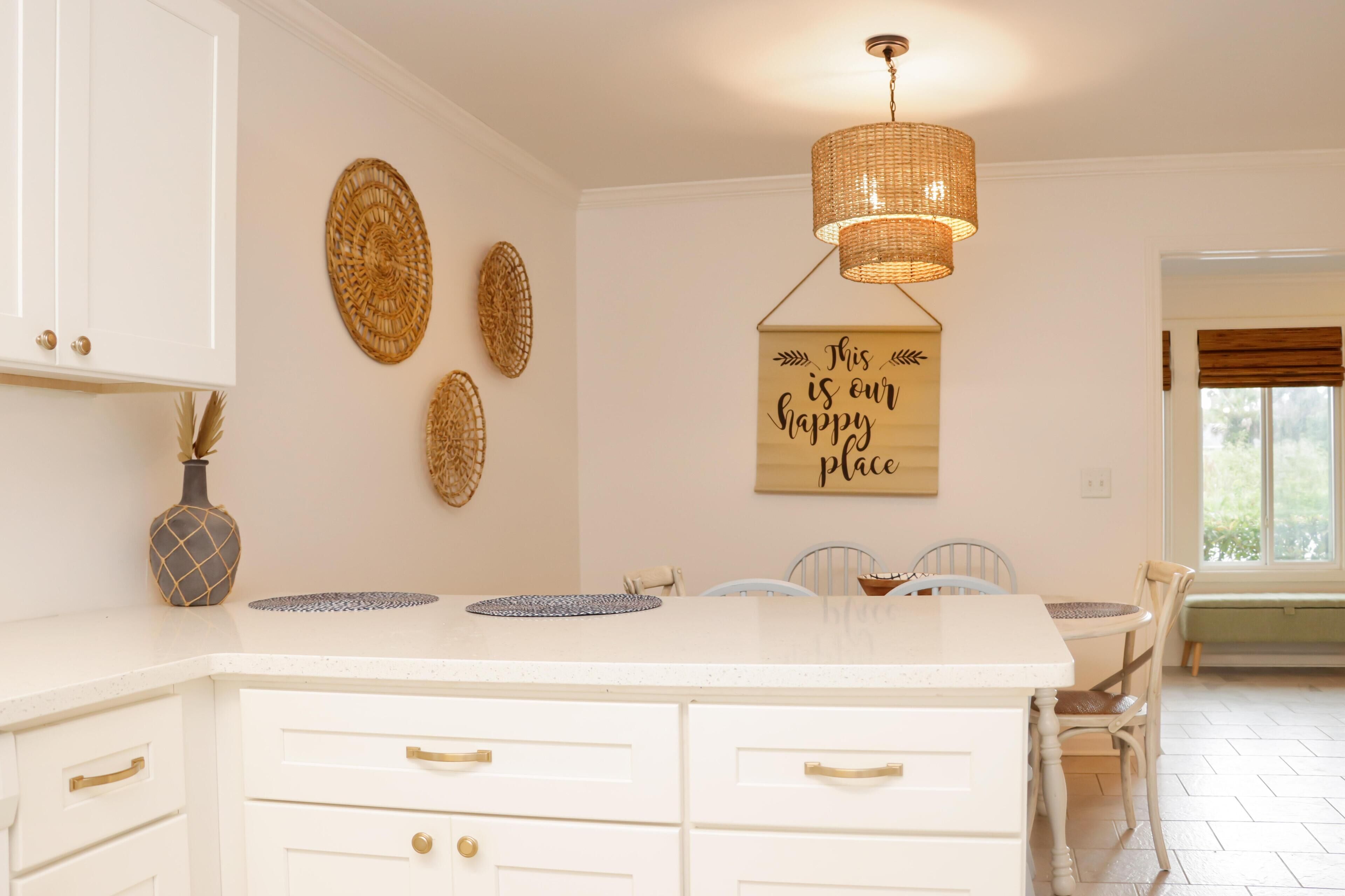 Una cocina con armarios blancos, una isla central y un colgante de luz.