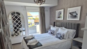 A modern bedroom with a large bed, a view to the outside, and two framed pictures on the wall.