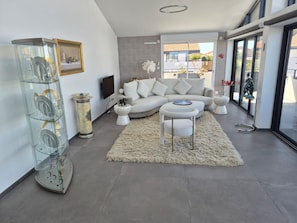 A modern living room with a sofa, a glass display unit, and a white rug. - La Perle cachée by Avecoeur (Marseillan)