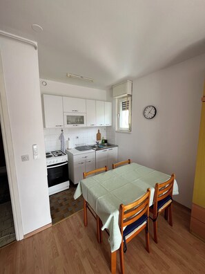 Kitchen and dining area with oven, stove, and dining table for four.