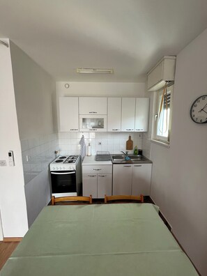 Compact kitchen with gas stove, sink, and small window.