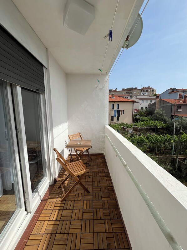 Enjoy the serene view from this balcony with a table and two chairs.