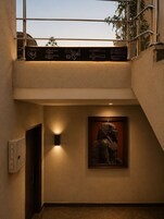 Un interior moderno con una escalera, una escultura enmarcada y una lámpara fijada a la pared.