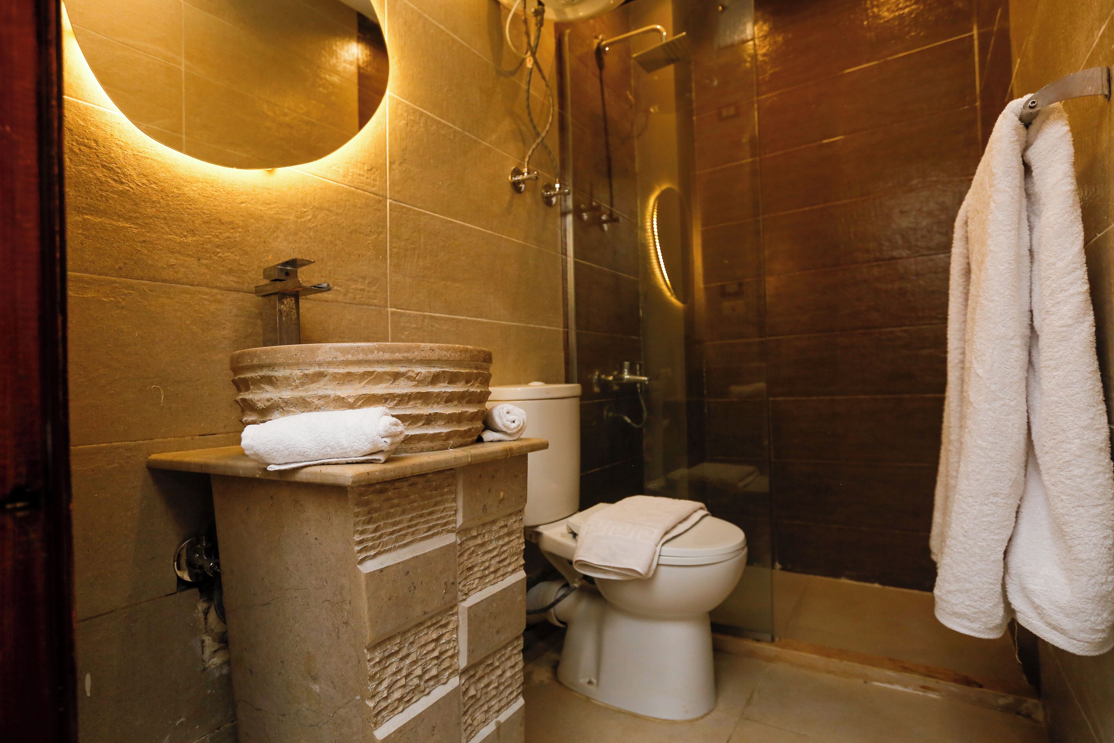 A bathroom with a stone sink, a toilet, and a glass shower enclosure.