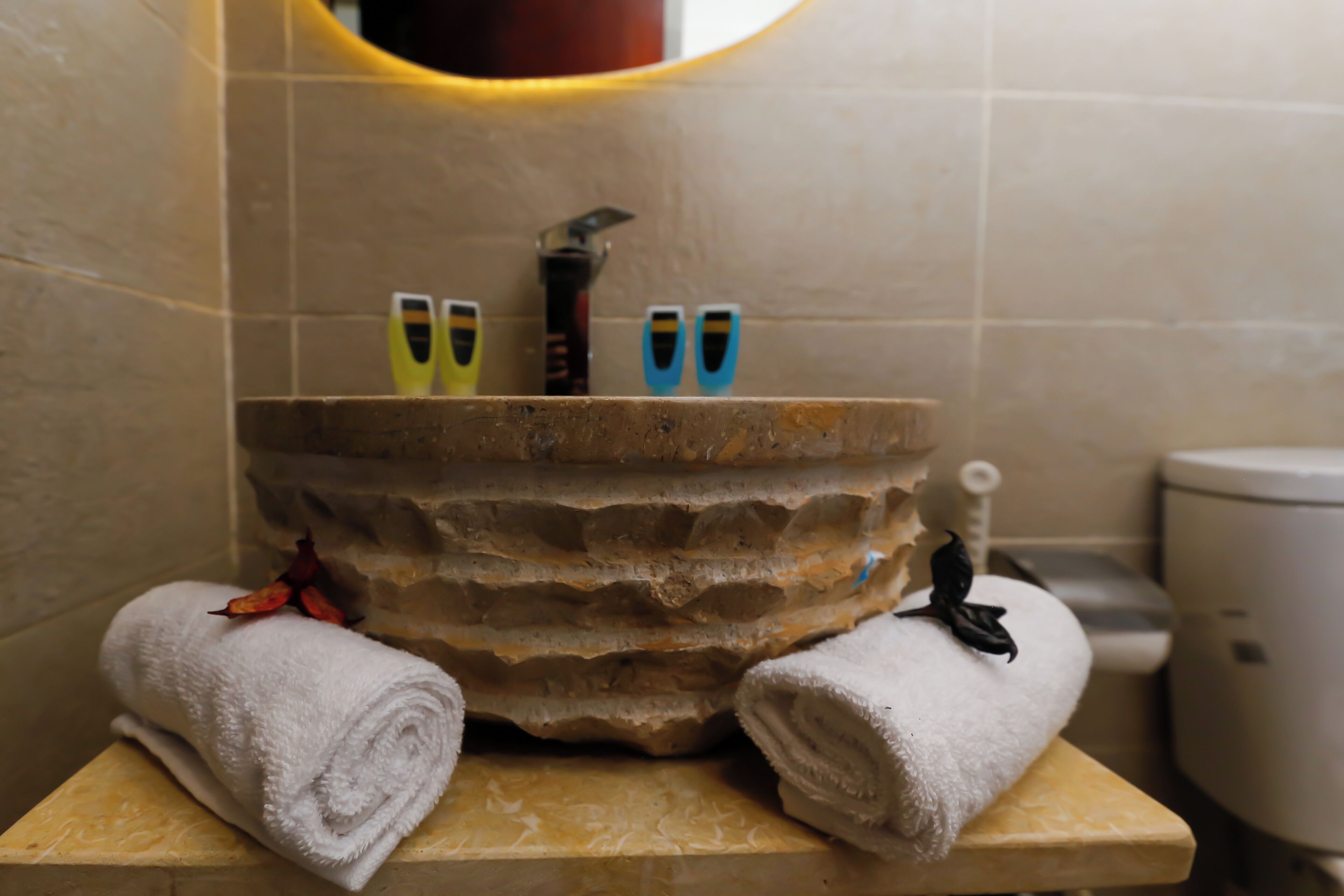 A bathroom with a stone sink, two towels, and a mirror.