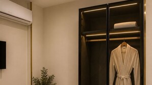 A modern bathroom with a glass-enclosed shower, a robe, slippers, and a potted plant. - Taj pyramids view inn (Giza)