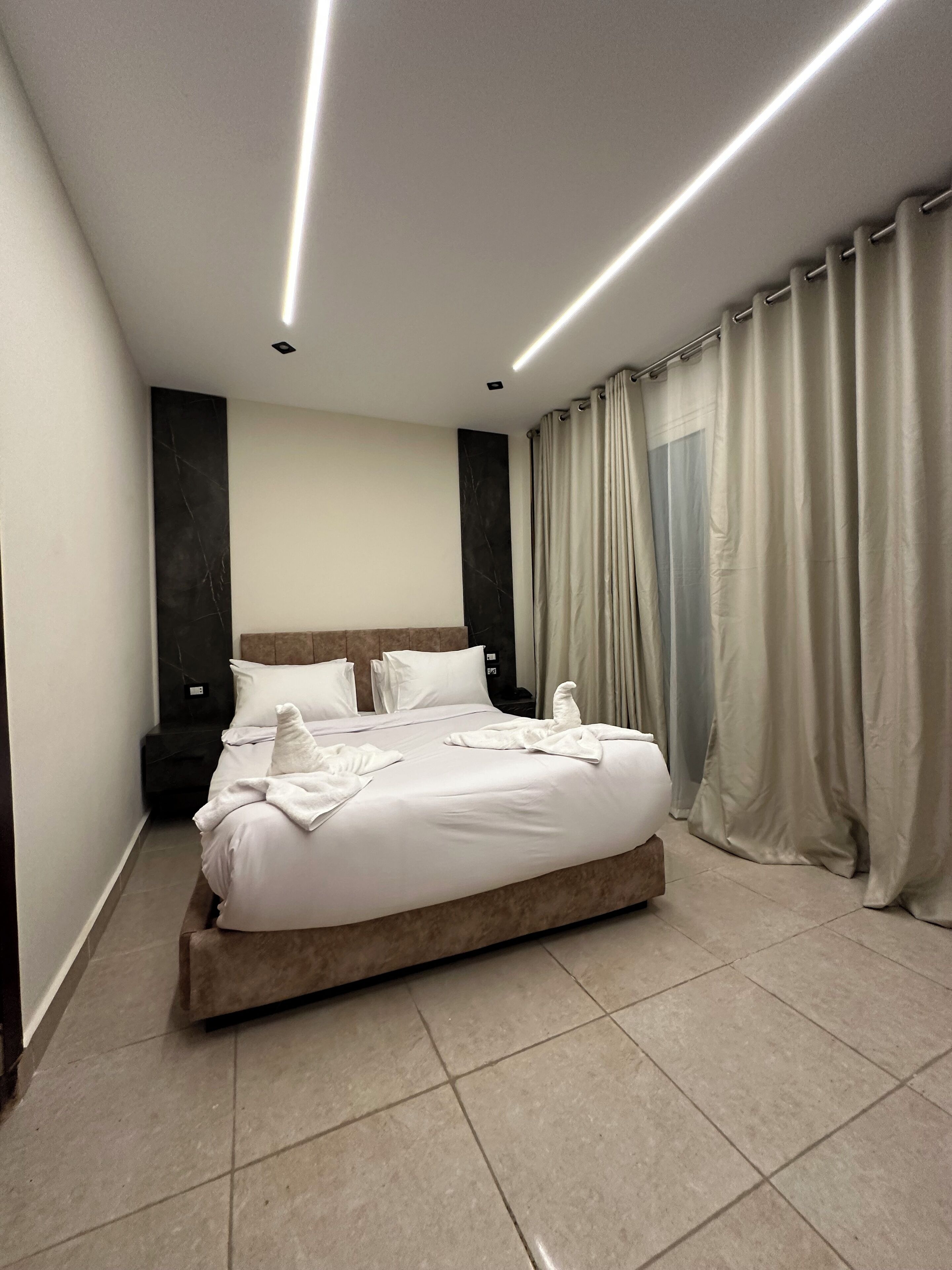 Un dormitorio moderno con una cama grande, un cabecero y una mesita de noche.