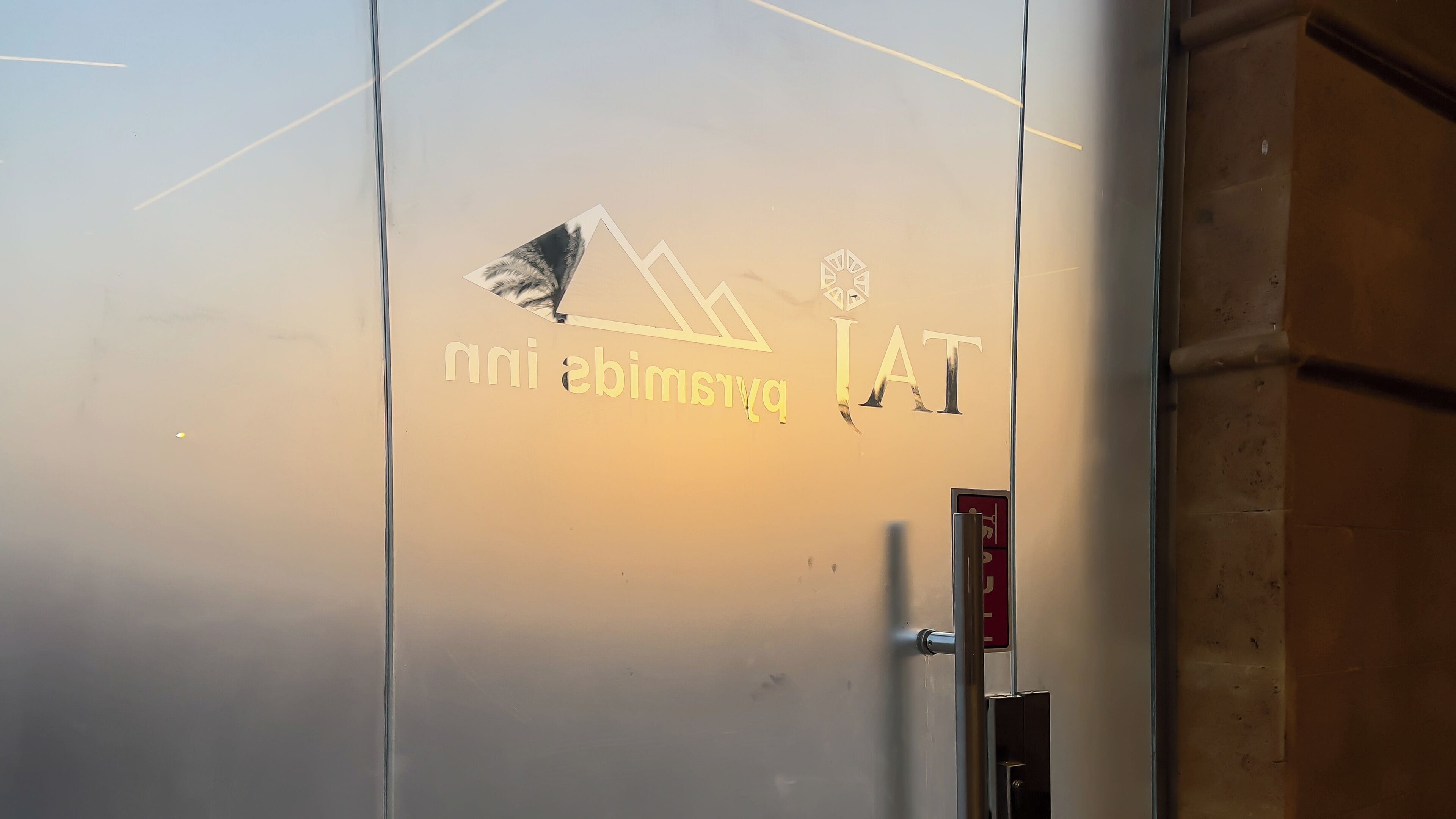A wall with a logo and text, a door handle, and a fire exit sign.
