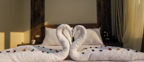 A bed with white sheets and a white blanket, a wooden headboard, and a white pillow.