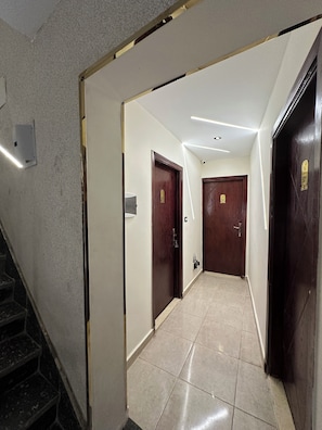 Stylish corridor with a tiled floor and textured walls, featuring wooden doors and a staircase.