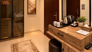 A modern hotel room with a wooden vanity, a large mirror, a bed, a sliding glass door to a closet, and a small rug. - Taj pyramids view inn (Giza)