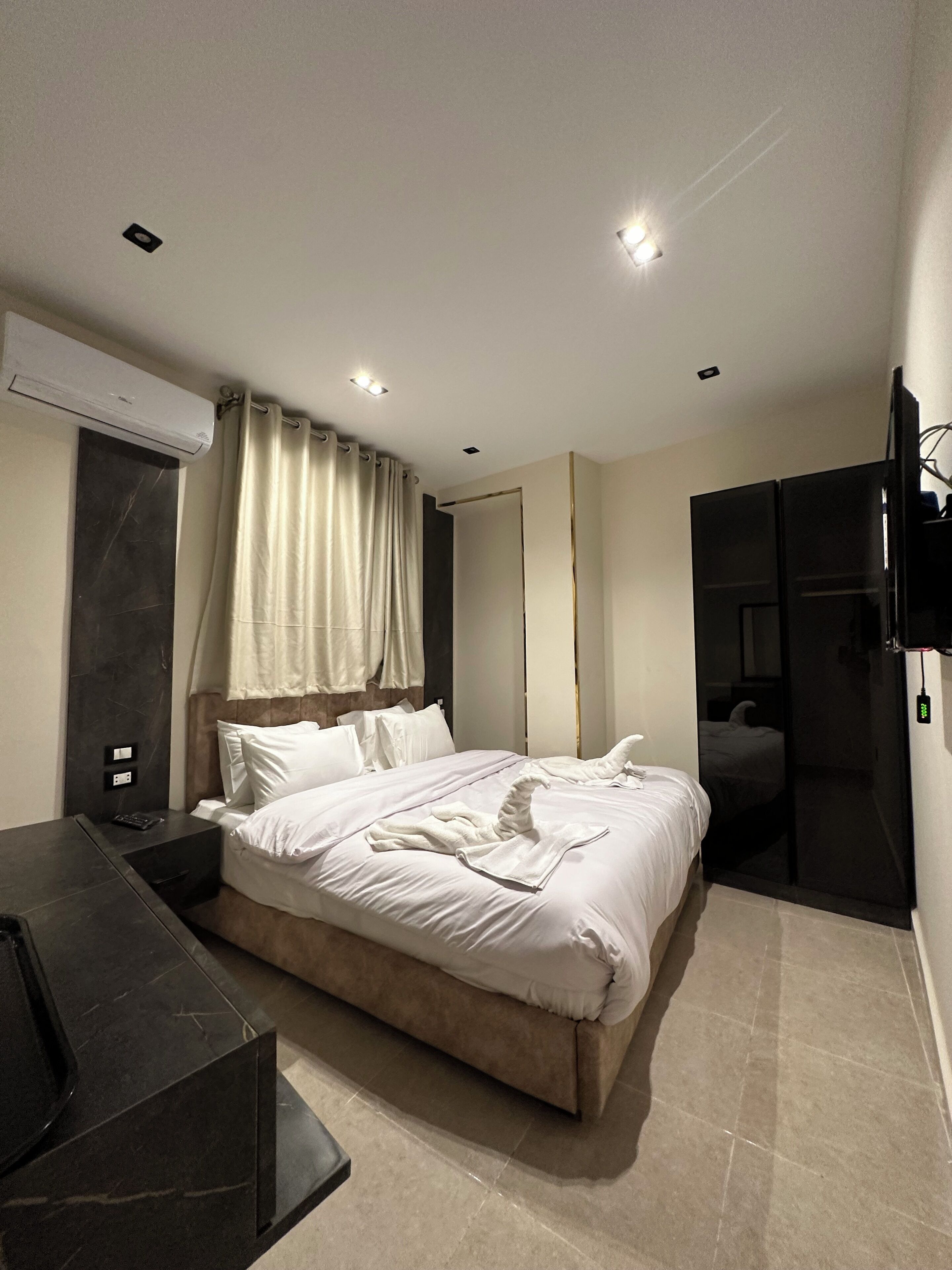 A modern hotel room with a large bed, a desk, and a flat-screen TV.