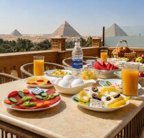 Una mesa de desayuno con diferentes platos, una botella de agua y vistas a las pirámides.