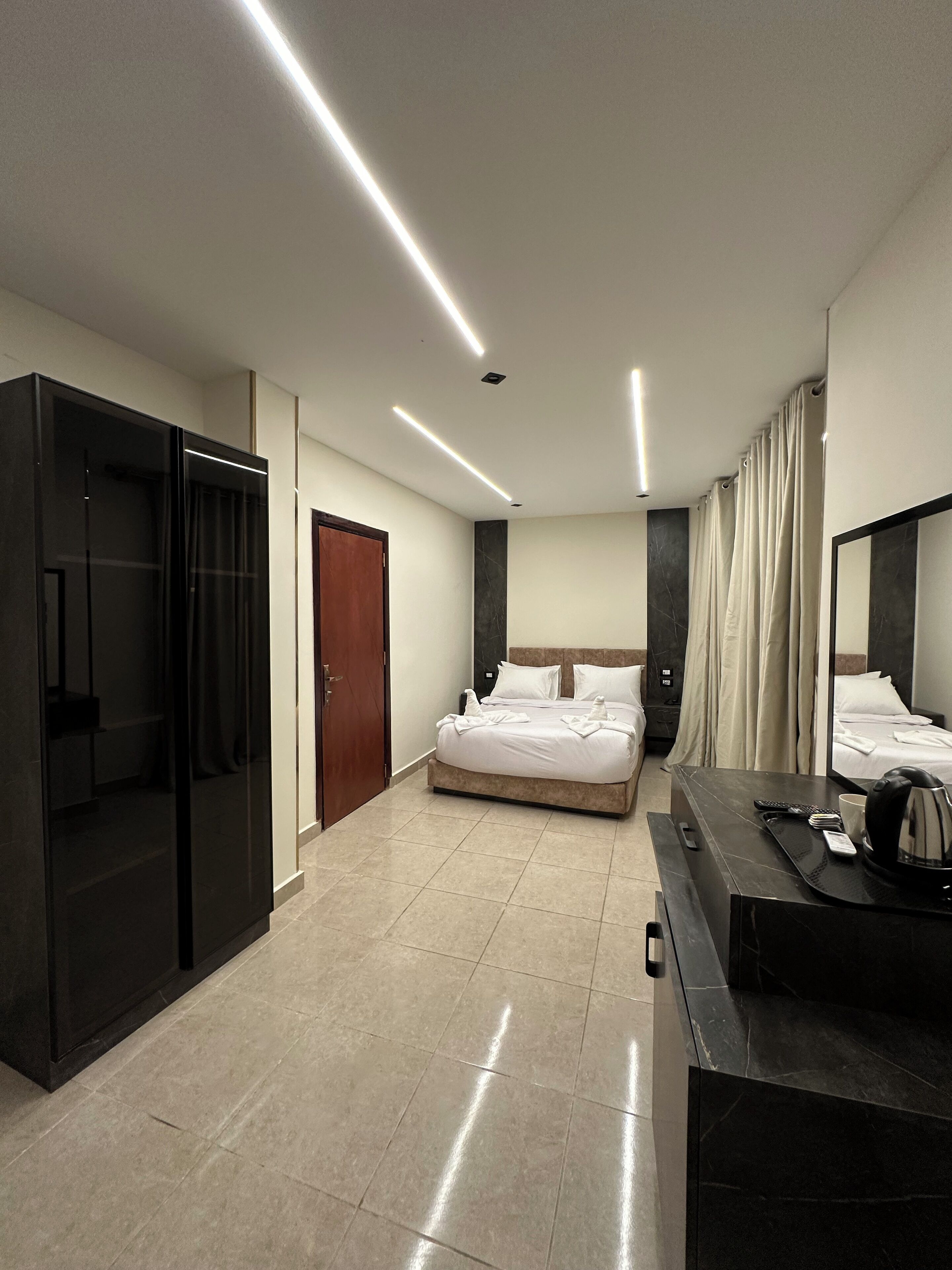 Una habitación de hotel moderna con una cama grande, una zona de escritorio separada, un armario y un baño con ducha e inodoro.