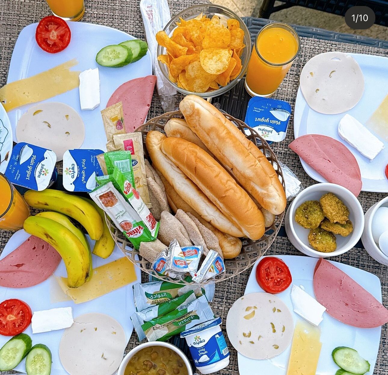 Un montaje para picnic con diversos alimentos, como sándwiches, papas fritas, fruta y bebidas.