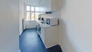 A narrow kitchen with white cabinets, a microwave, and a washing machine. - Cool 1-bed Apartment in Rhus (Aarhus)