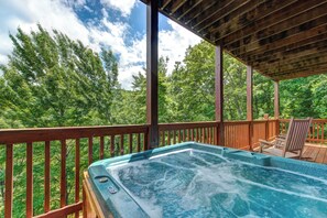 Un jacuzzi en una terraza de madera con vista a un bosque.