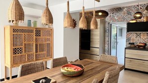 Un comedor moderno con una mesa de madera, sillas de mimbre e iluminación colgante tejida.