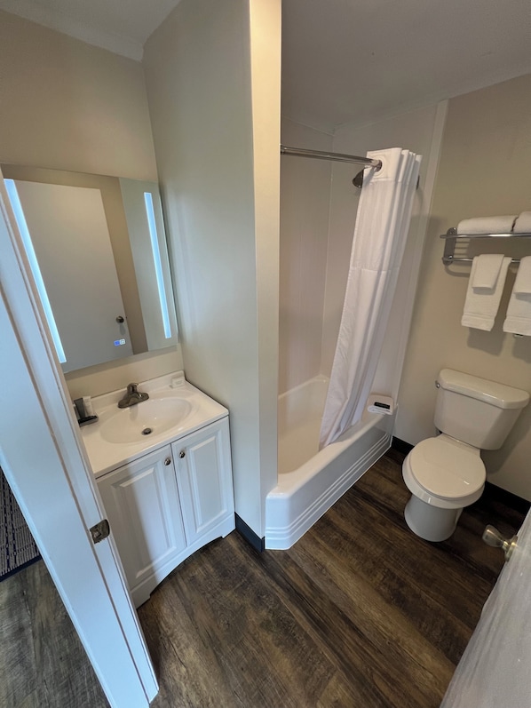 Un baño con lavamanos blanco, espejo, inodoro y ducha.
