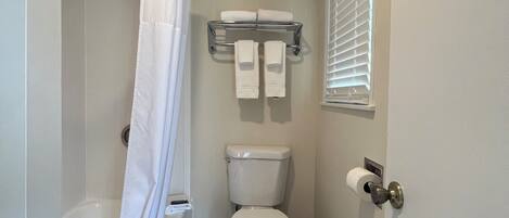 Une salle de bain équipée de toilettes, d’une douche et d’un porte-serviettes.