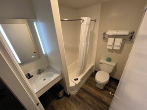 A bathroom with a white sink, toilet, and shower curtain. - River Valley Inn (West Hatfield)