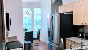 A modern kitchen with granite countertops, stainless steel appliances, and a dining area with a table and chairs.