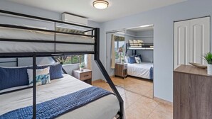 Una habitación con literas, una mesita de noche pequeña con lámpara y vistas a través de una puerta de cristal.