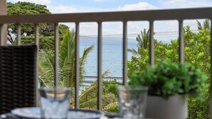 Un balcón con vista al mar, plantas en macetas y mobiliario de exterior.