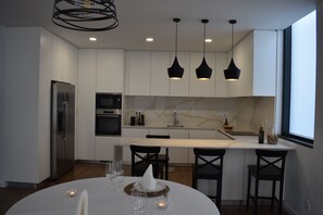 A modern kitchen with white cabinetry, a built-in oven, and a dining area with a round table and chairs.