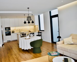 A modern kitchen with white cabinets, a marble countertop, and pendant lighting.