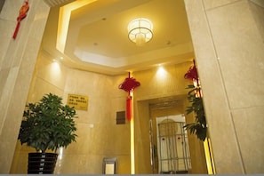 A lobby with a reception desk, a potted plant, and a sign on the wall. - Yiju Boutique Hotel (Yueqing)