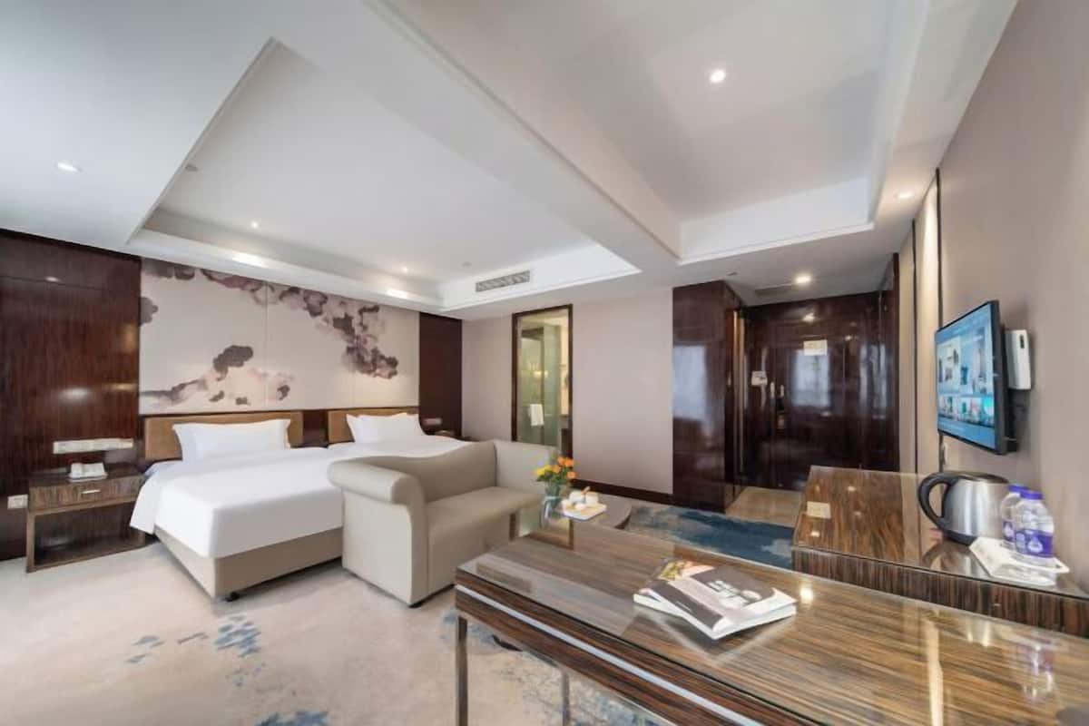 Een hotelkamer met een bed, een bank, een bureau, een spiegel en een televisie.