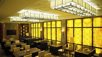 A hotel lobby with multiple seating areas, including tables and chairs, and a large chandelier.