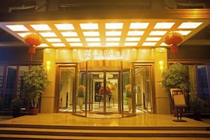 A hotel entrance with a revolving door, potted plants, and a sign above the door. - Yiju Boutique Hotel (Yueqing)