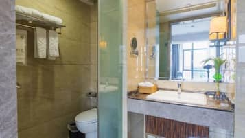 Un baño moderno con cabina de ducha de vidrio, inodoro blanco, tocador con espejo y perchero.