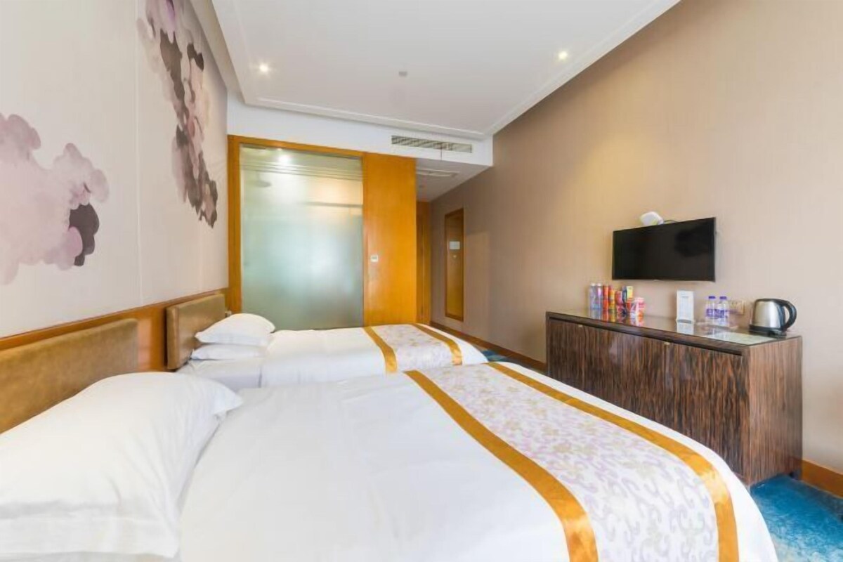 A hotel room with two beds, a TV, and a minibar.