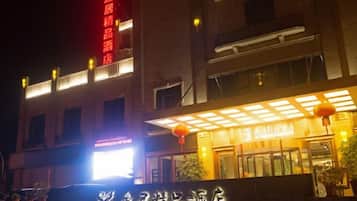 A hotel with a prominent sign, a covered entrance, and a brightly lit facade.