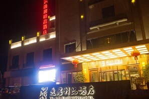 A hotel with a prominent sign, a covered entrance, and a brightly lit facade. - Yiju Boutique Hotel (Yueqing)