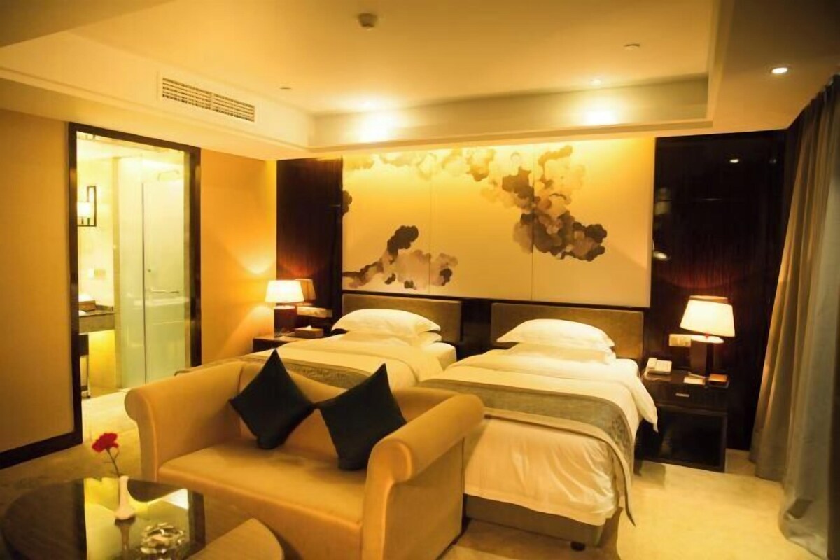 A hotel room with two beds, a sofa, a small table, and a wall art piece.