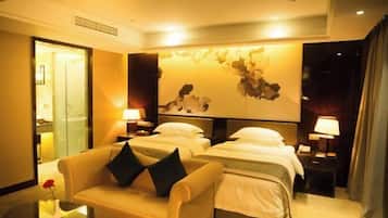 Habitación de hotel con dos camas, un sofá, una mesita y una obra de arte en la pared.