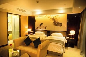 Ein Hotelzimmer mit zwei Betten, einem Schlafsofa, einem kleinen Tisch und einem Wandbild.