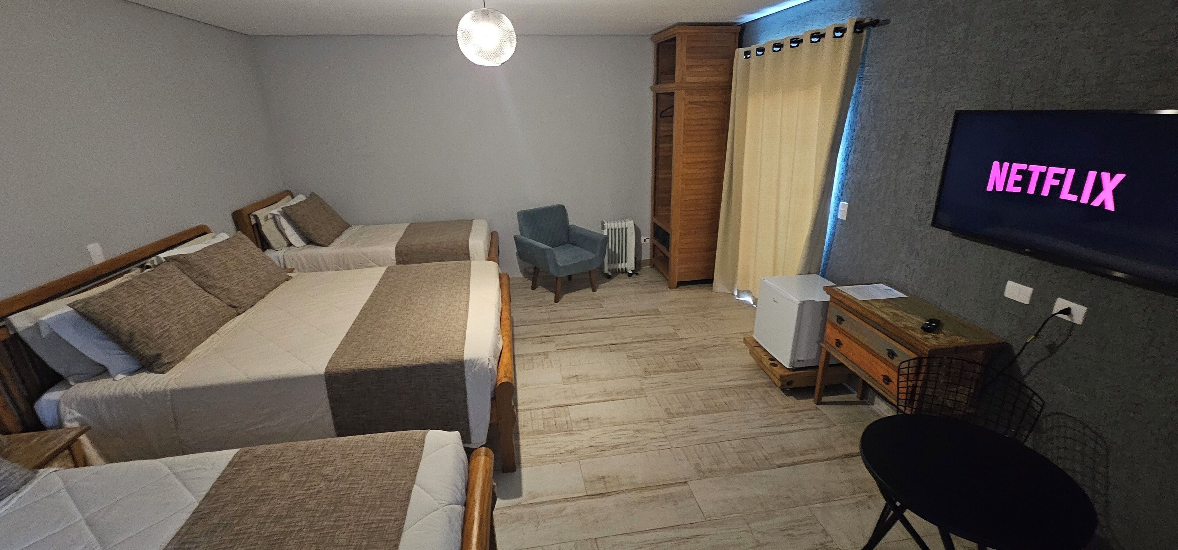 A hotel room with two beds, a TV displaying 'NETFLIX', a desk with a computer, and a chair.