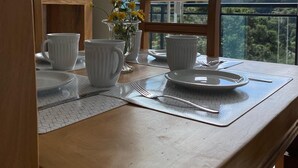 Een eettafel met witte borden, kopjes en een vaas gele bloemen.