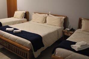 Hotellihuone, jossa on kaksi erillistä sänkyä. Jokaisessa sängyssä on puinen pä äty ja yöpöydällä on puhelin. Sängyillä on sininen peitto.