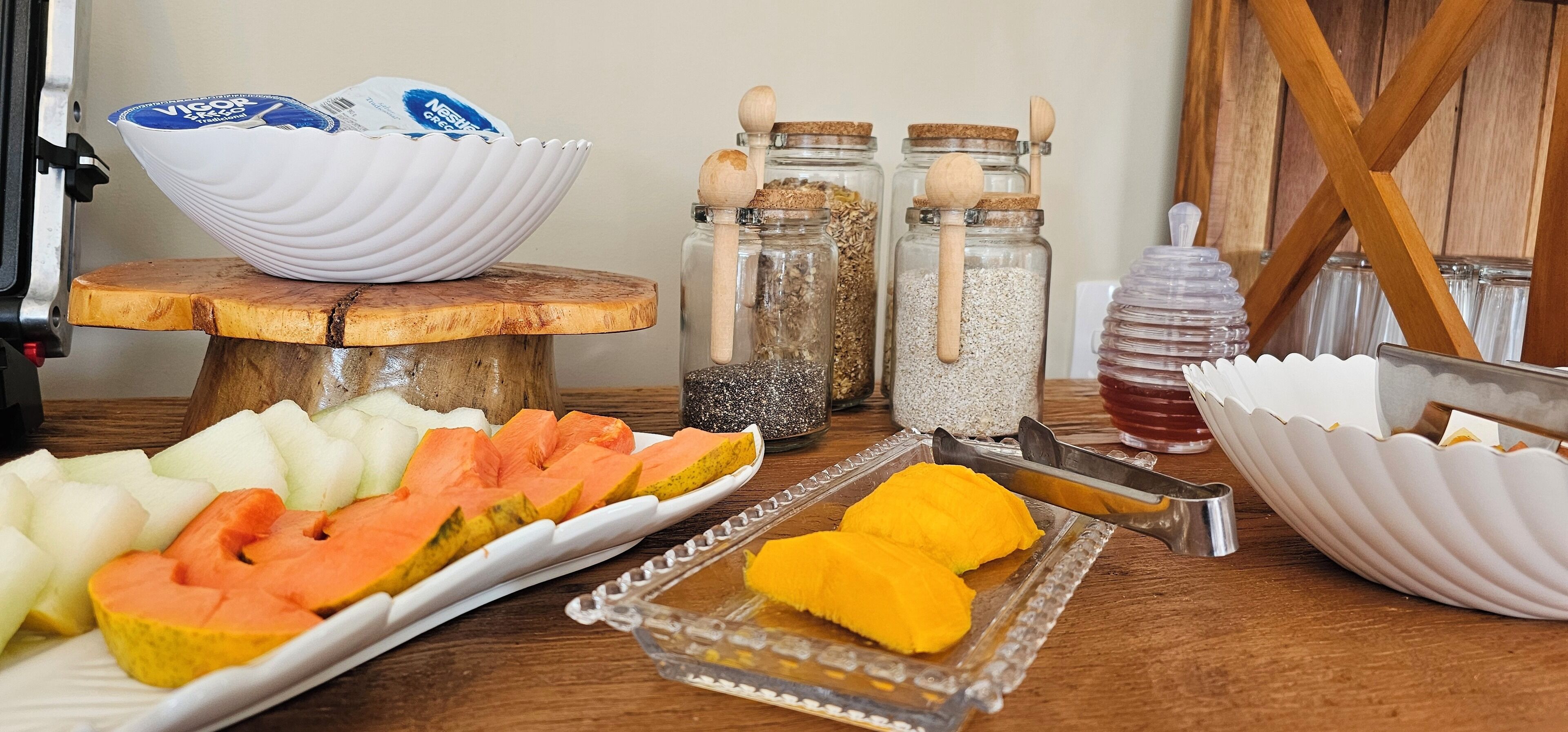 A table with various food items, including sliced fruits and jars with wooden scoops.